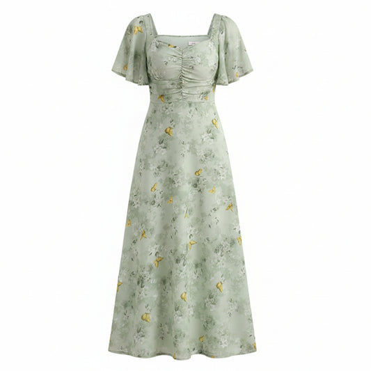 Woman wearing a light green floral dress in a room with white curtains.