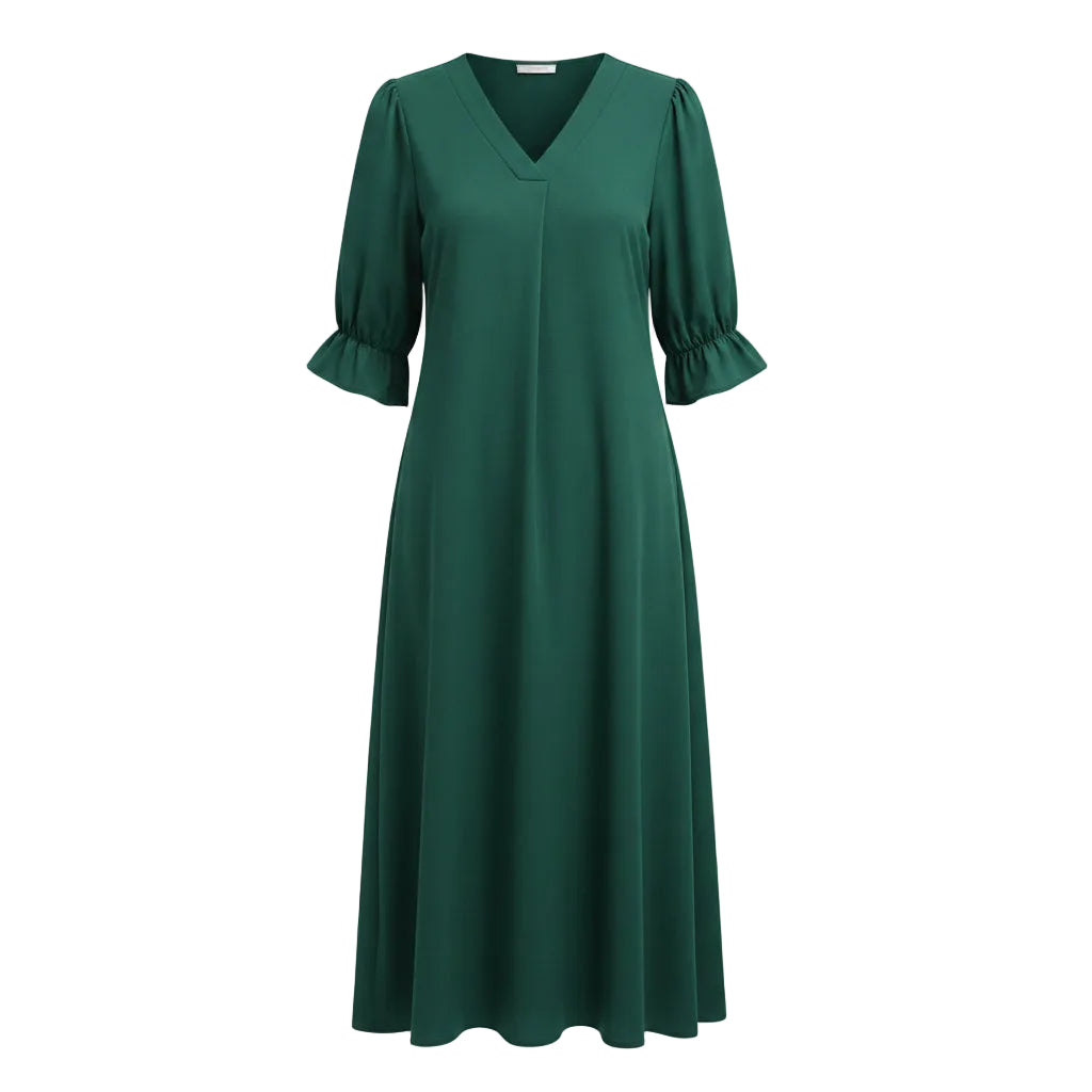 Woman wearing a green dress with puff sleeves against a white wall.