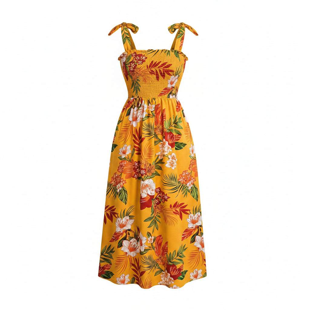 Woman wearing a yellow floral dress in a bright room with a plant and chair.
