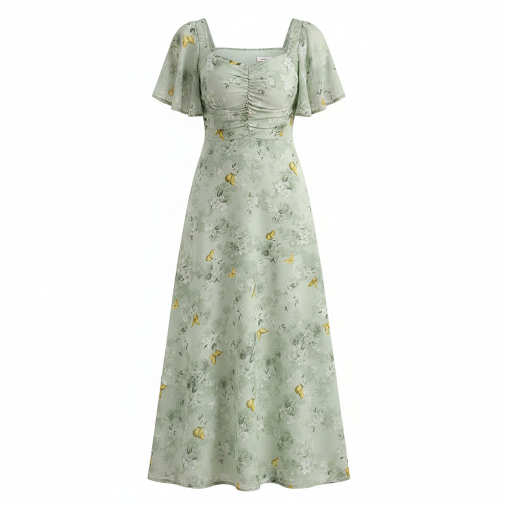 Woman wearing a light green floral dress in a room with white curtains.