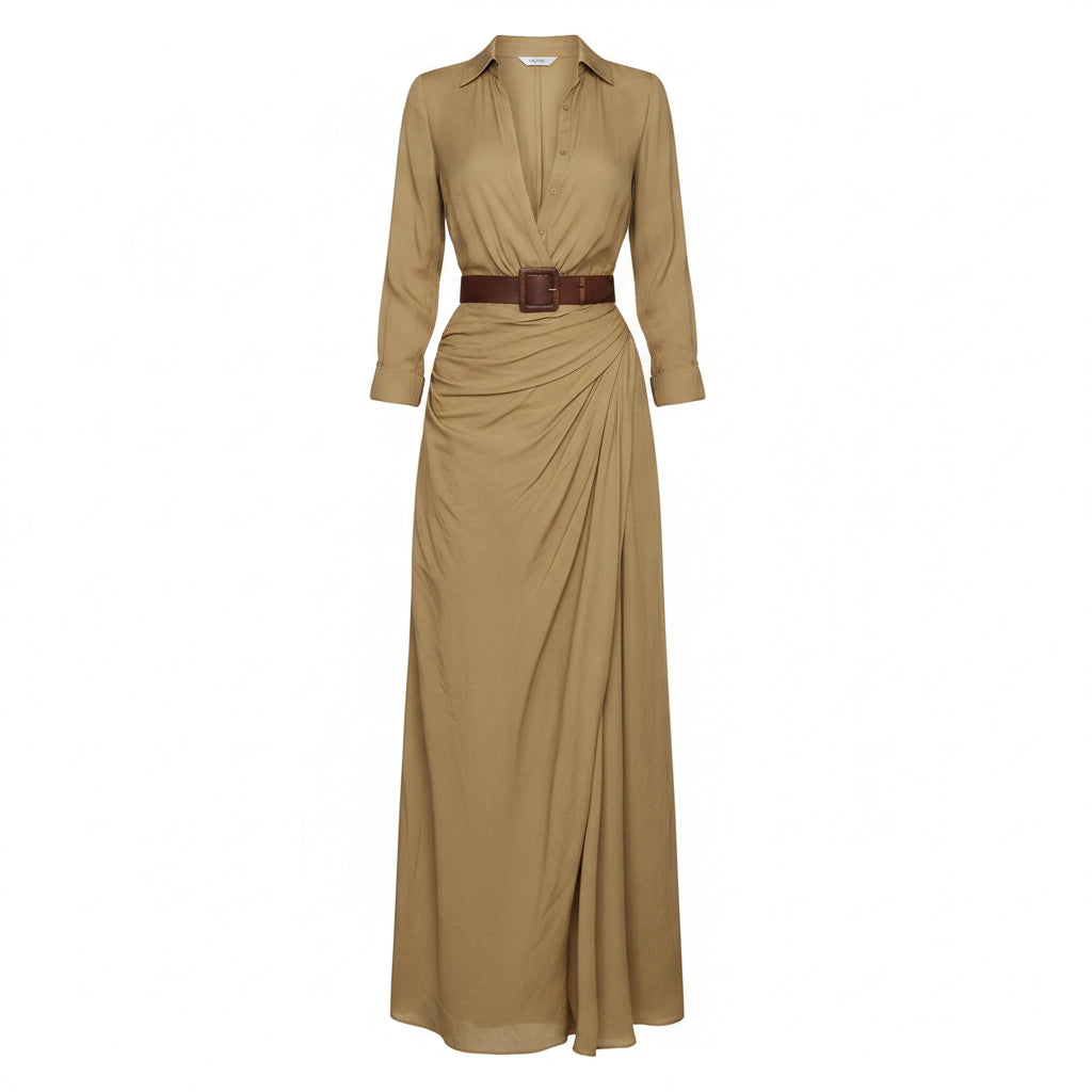A woman models a flowing tan maxi shirt dress with a deep V-neck, long sleeves rolled to the forearm, and a brown leather belt. She is carrying a woven straw tote bag and wearing flat brown sandals, set against a textured light gray concrete wall.