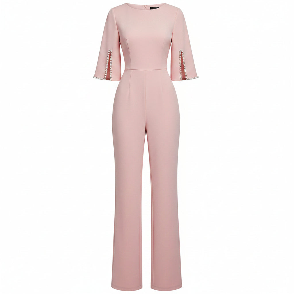 Woman wearing a pink jumpsuit with pearl embellishments against a plain background