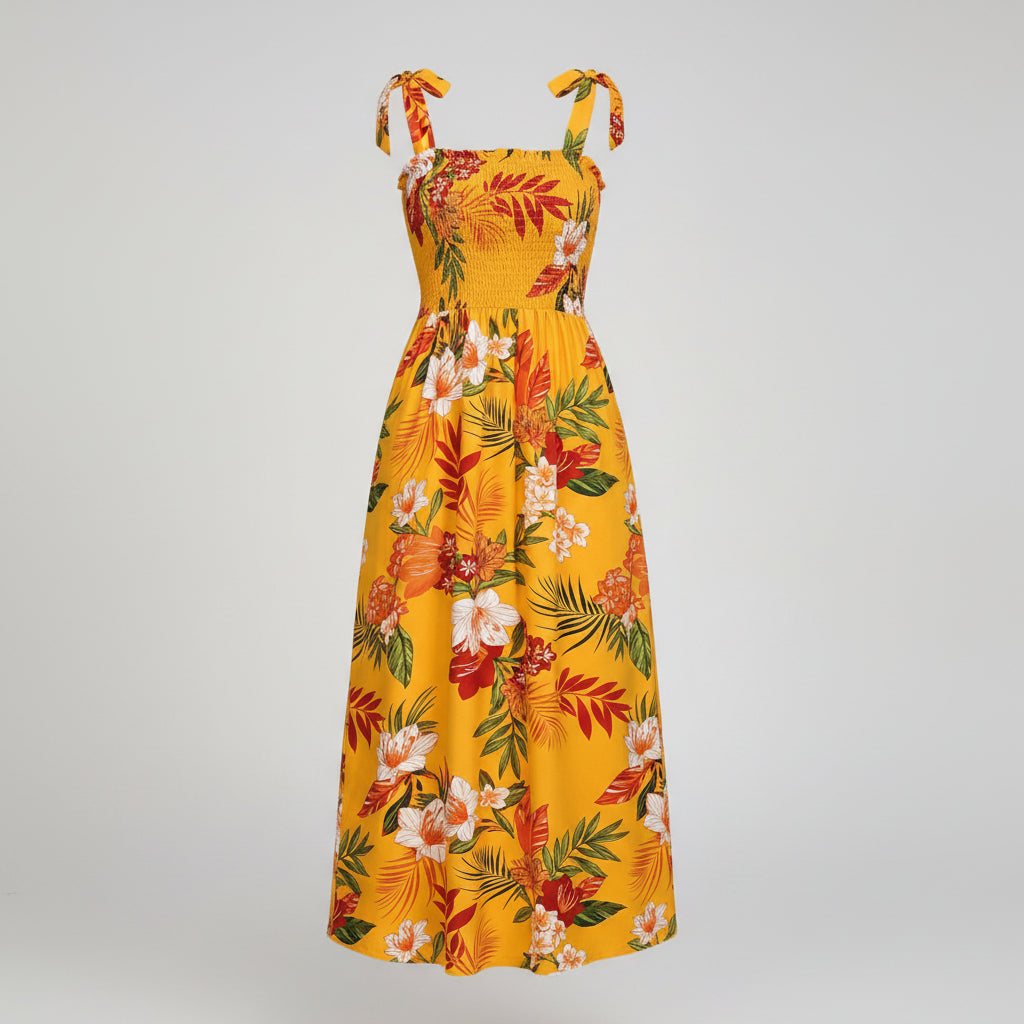 Woman wearing a yellow floral dress in a bright room with a plant and chair.