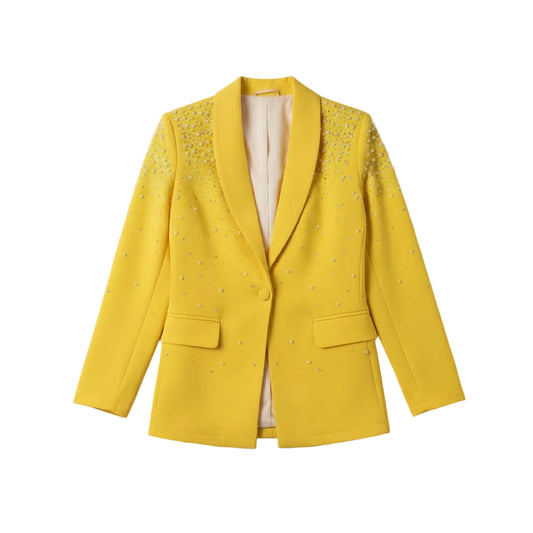 Person wearing a bright yellow blazer with rhinestone embellishments on a gray background