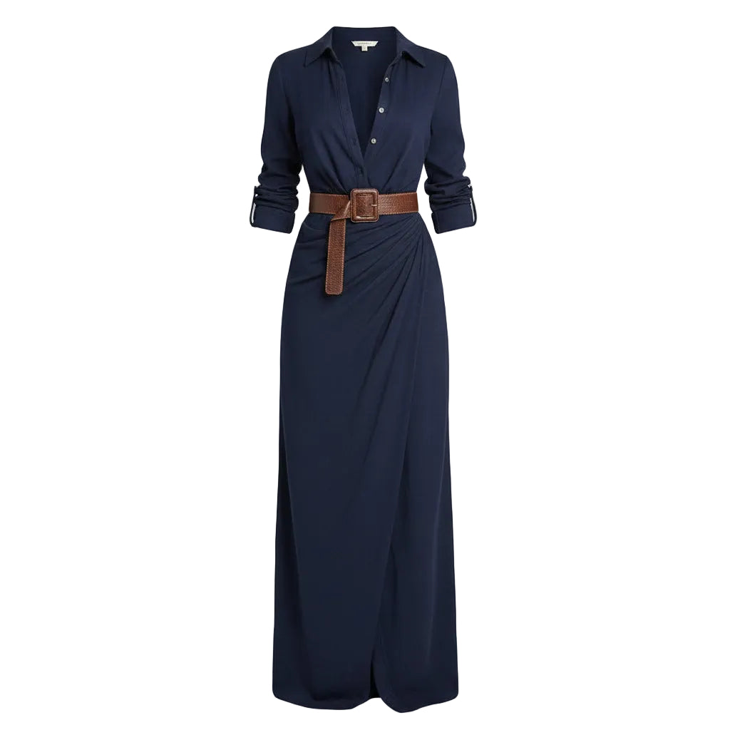 Woman wearing a long navy dress with a brown belt and holding a woven bag against a plain background