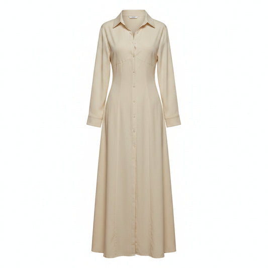 Woman wearing a long beige dress with a high slit in a room with white walls and a window.