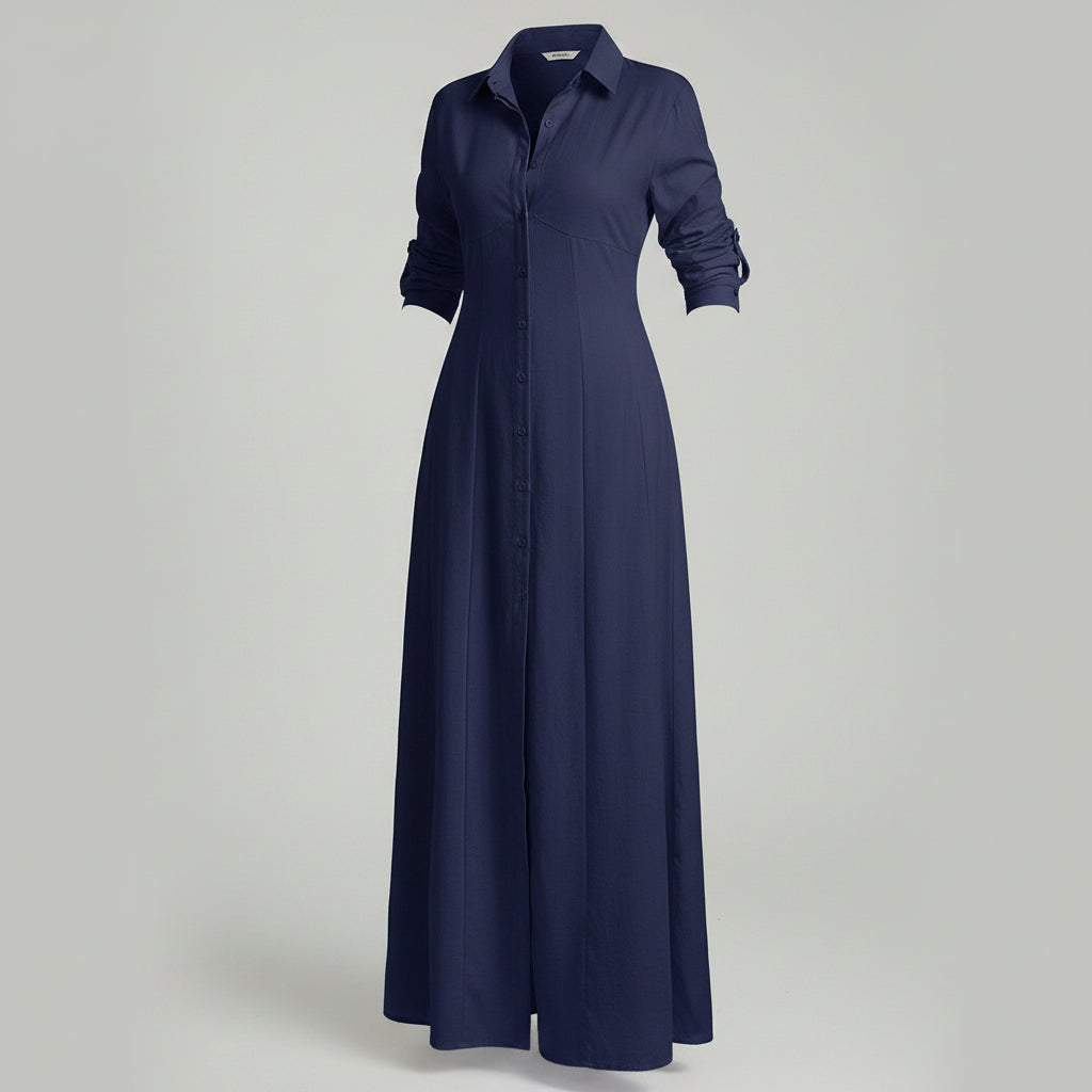 Woman wearing a long navy dress with a slit in a room with white walls and wooden flooring.