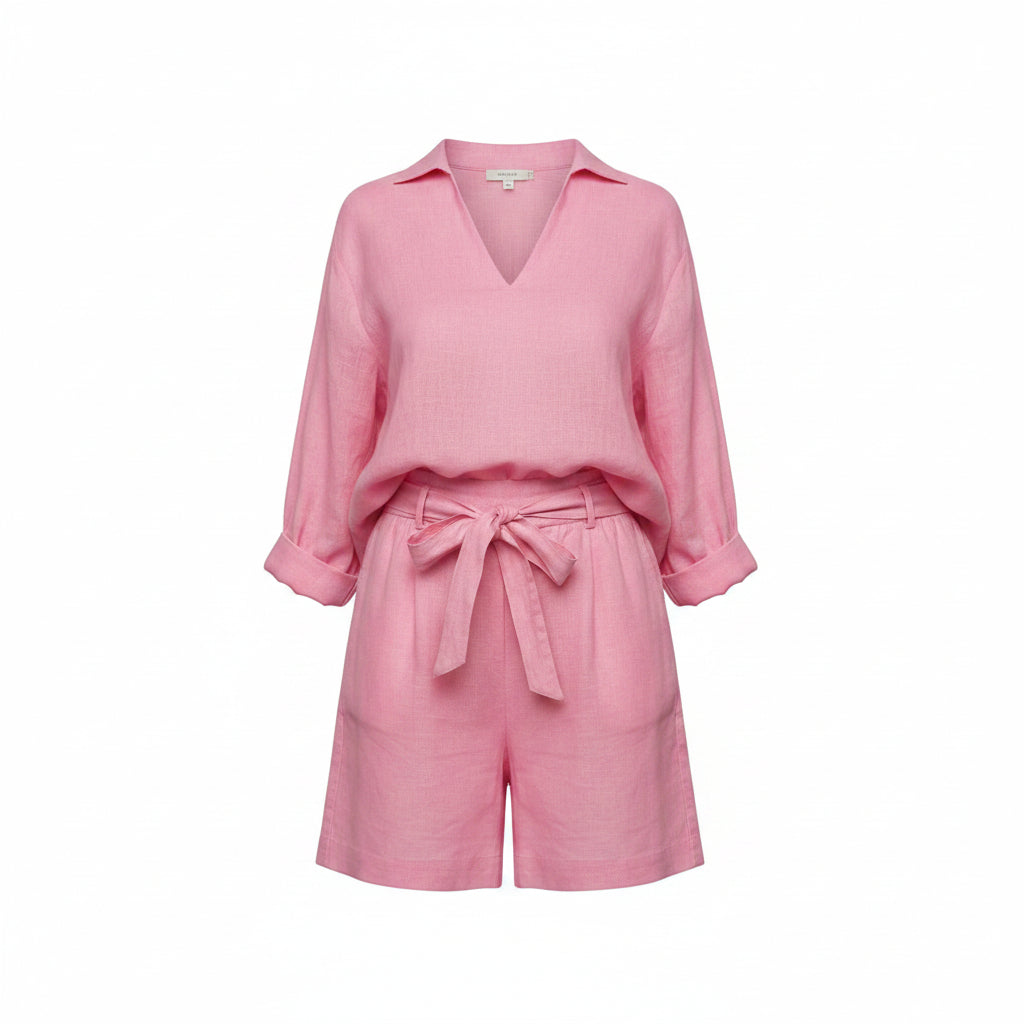 Person wearing a pink outfit holding a beige bag on a light wooden floor.