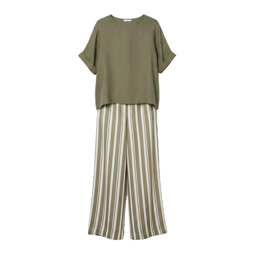 Woman wearing a green top and striped pants against a gray background