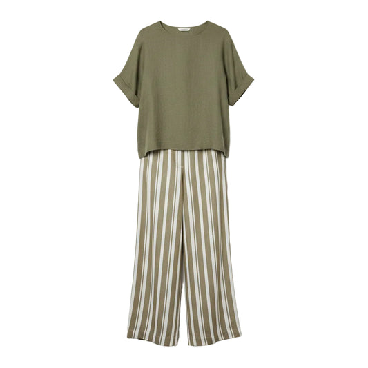 Woman wearing a green top and striped pants against a gray background
